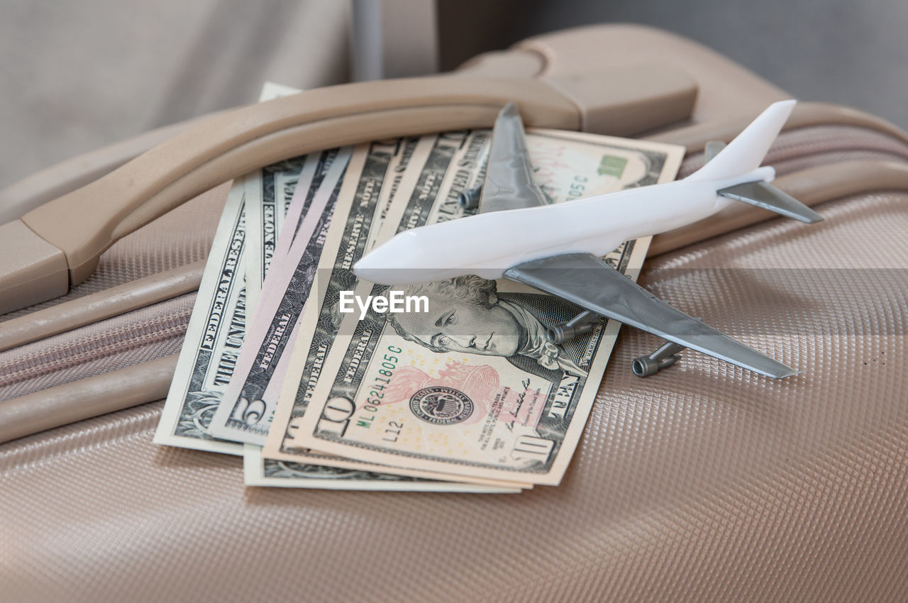 Dollar banknote money lay on luxury tourist baggage with airplane model, planning and prepare for 