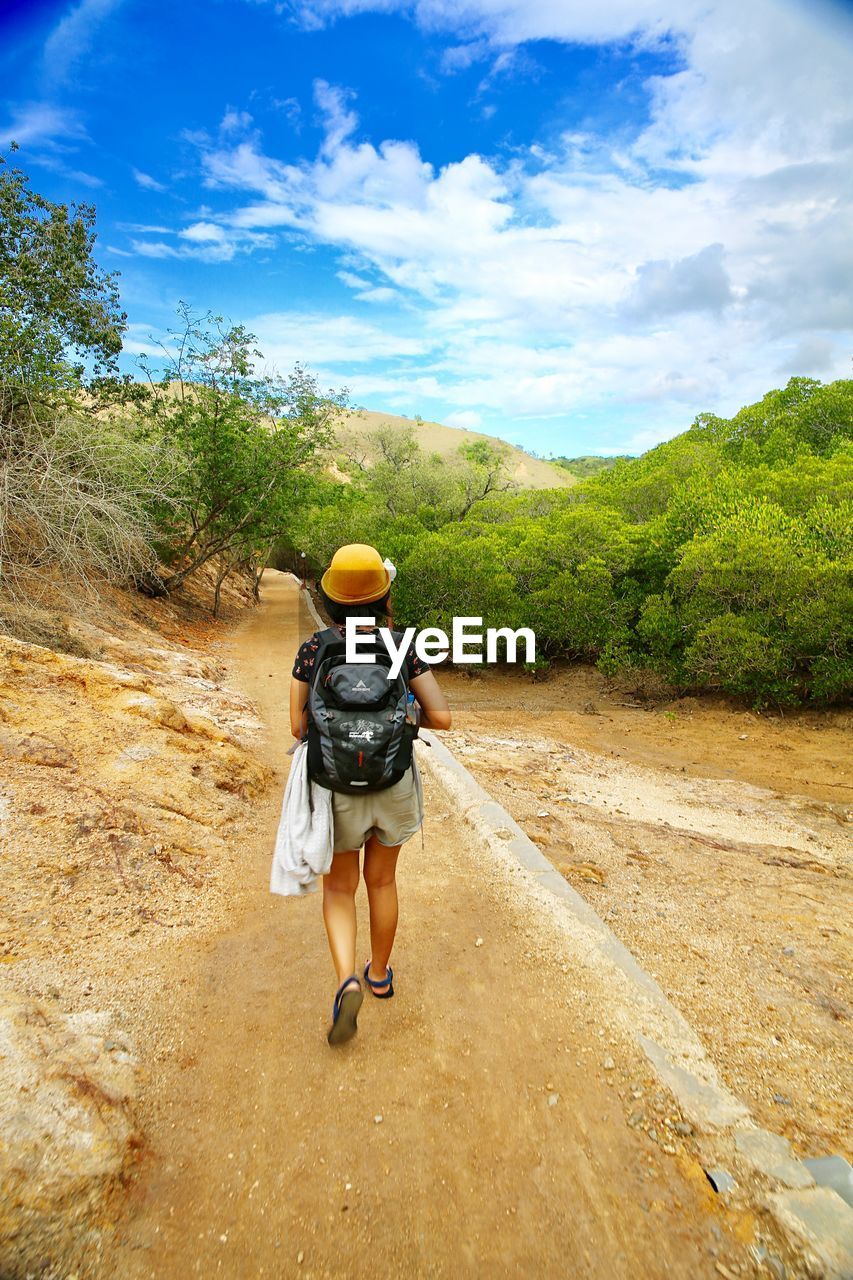 FULL LENGTH REAR VIEW OF MAN WALKING ON MOUNTAIN ROAD