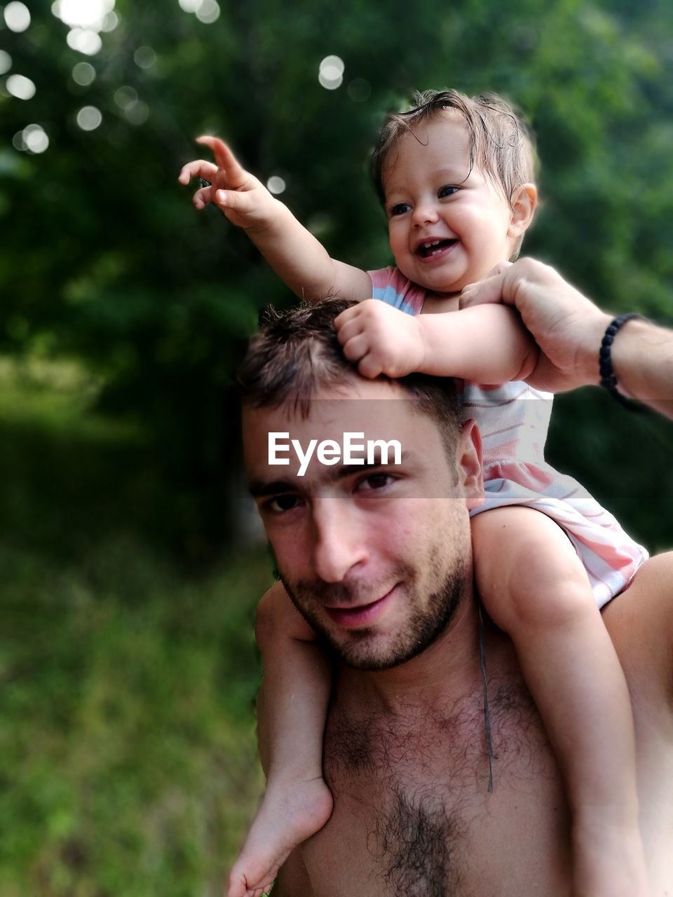 Close-up portrait of father carrying daughter on shoulder at park