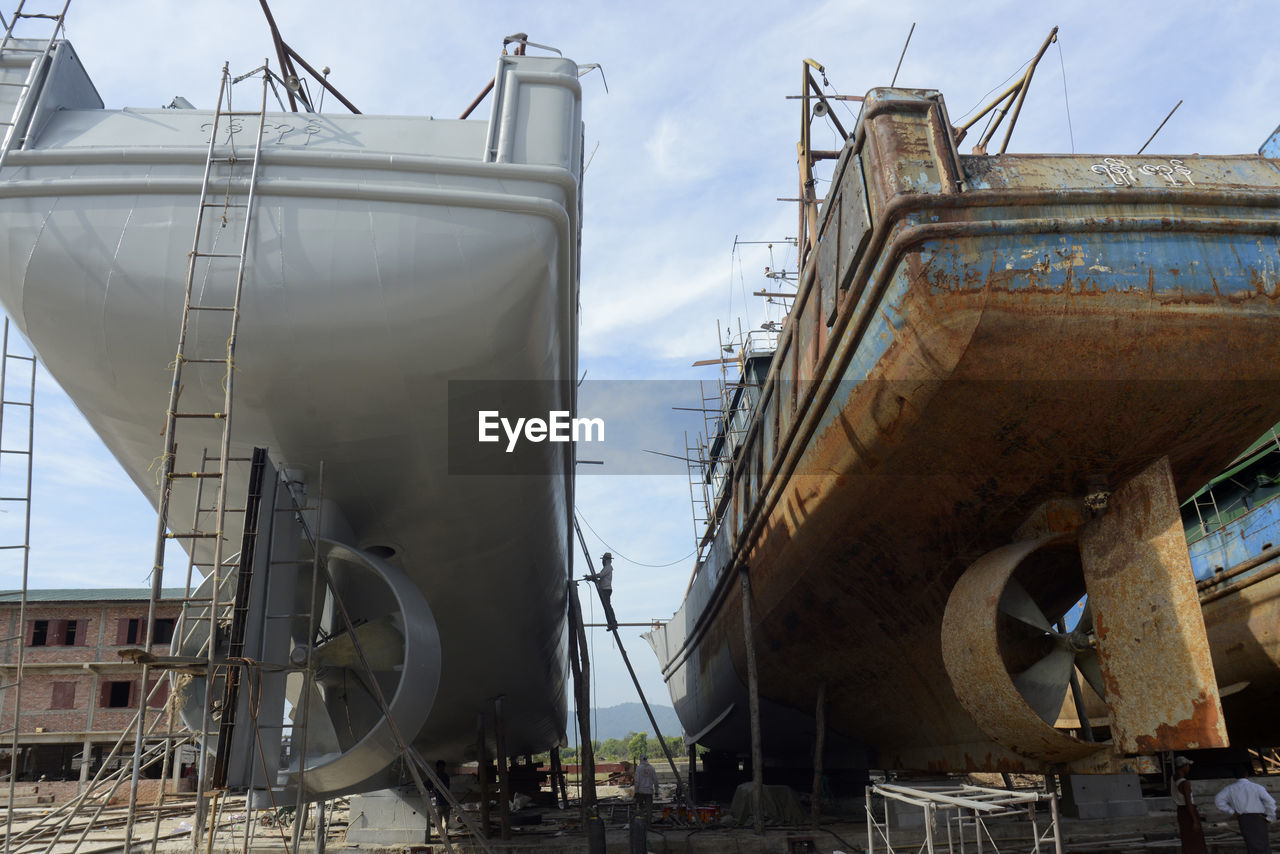 Low angle view of ships at construction site against sky