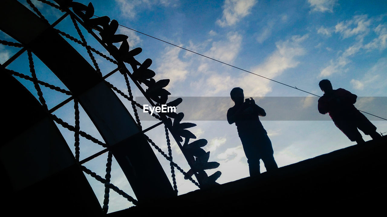 LOW ANGLE VIEW OF SILHOUETTE MEN AGAINST BUILT STRUCTURE