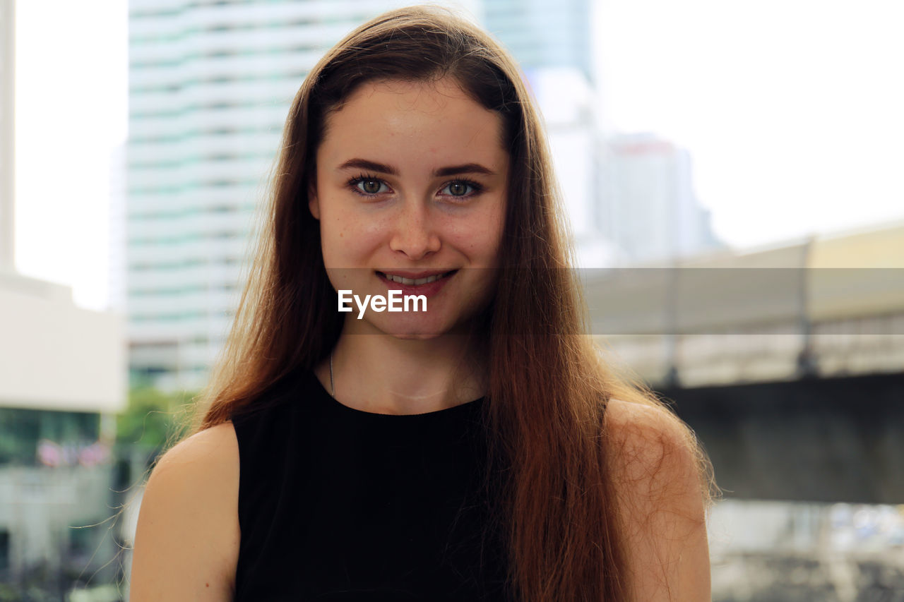 PORTRAIT OF A SMILING YOUNG WOMAN OUTDOORS