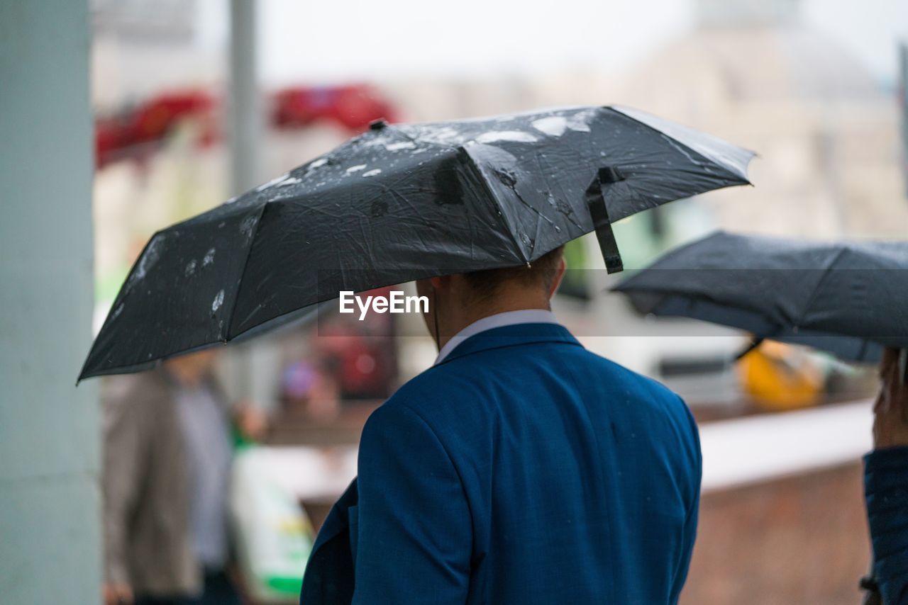 Man with umbrella walking on wet street