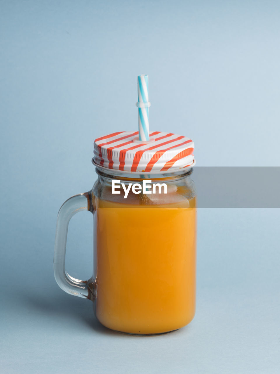 A jar of peach juice on blue background