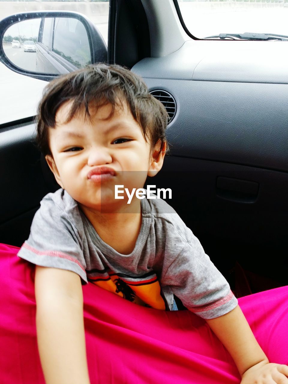 Portrait of cute boy making face in car