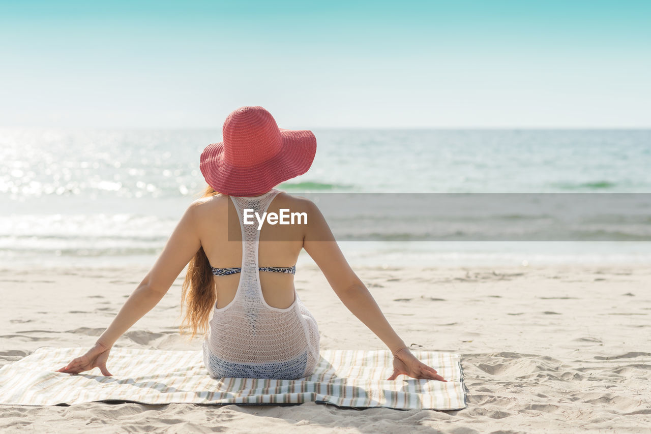 Rear view of woman sitting on beach