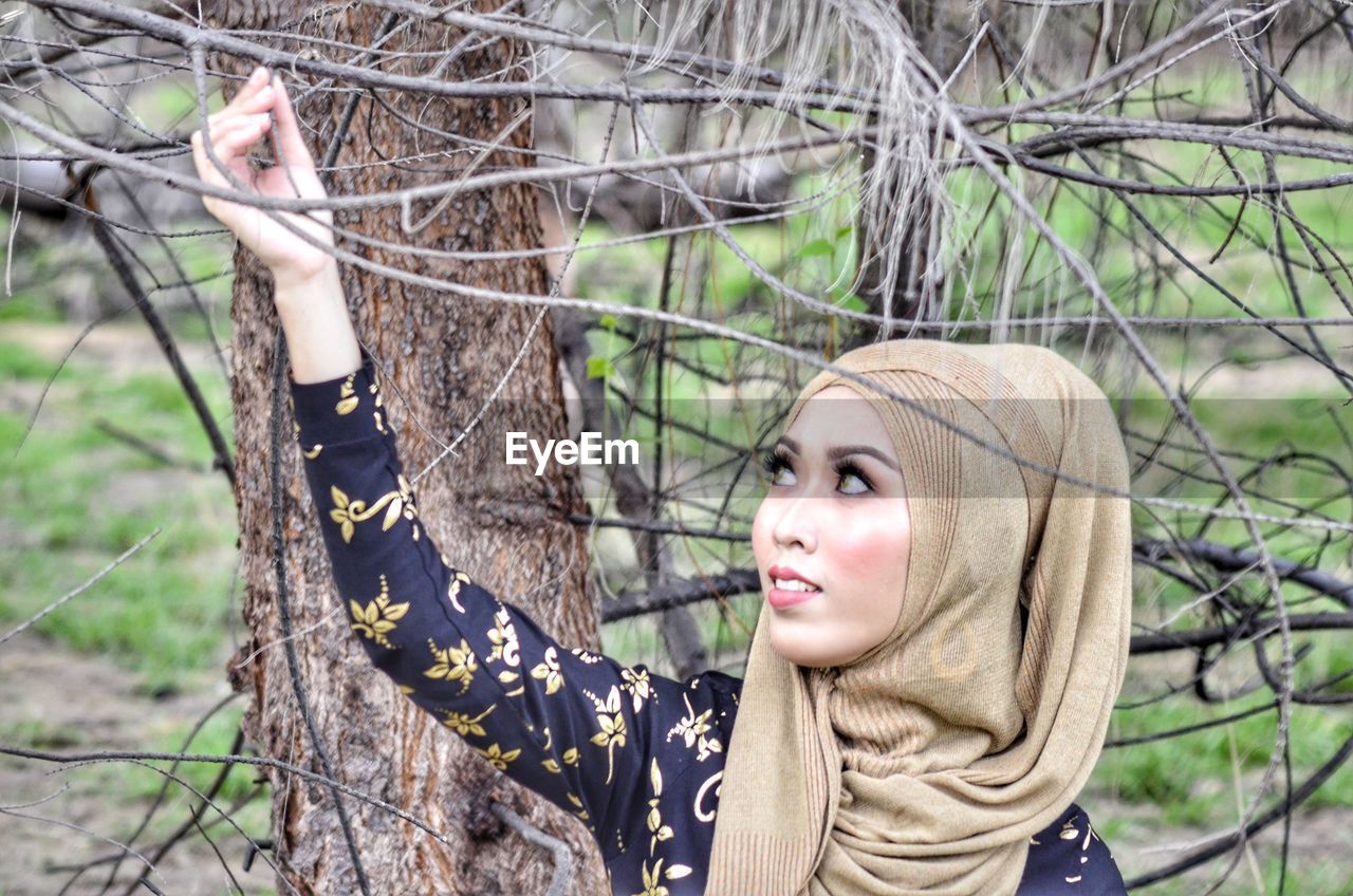 Woman wearing headscarf standing by tree