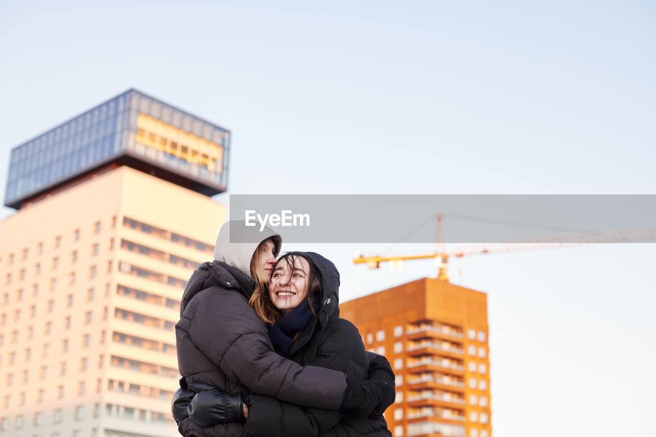 Female couple hugging in modern neighborhood