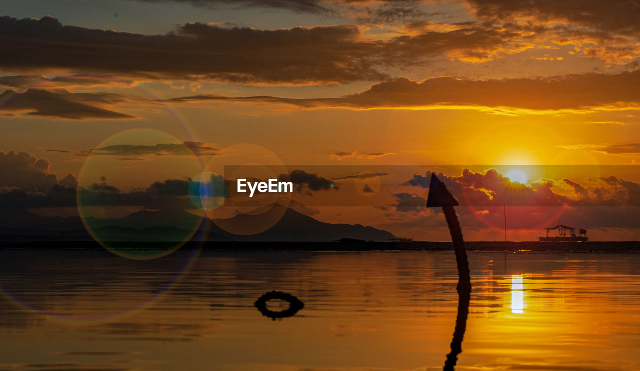 SCENIC VIEW OF BEACH AGAINST ORANGE SKY