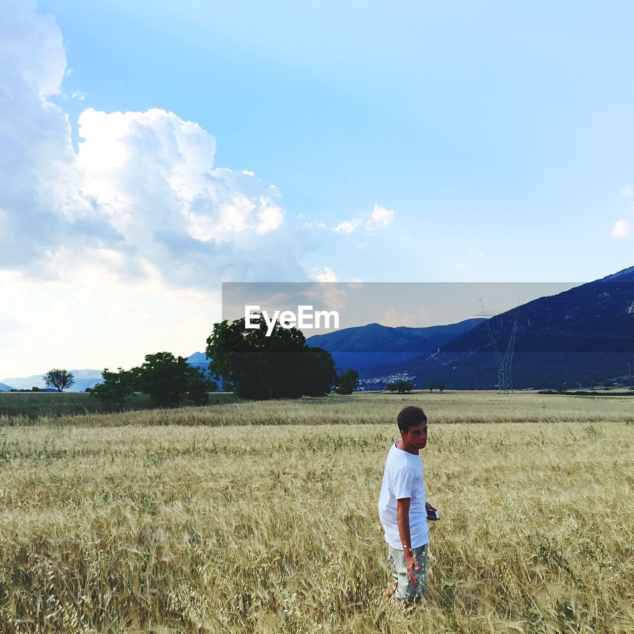 REAR VIEW OF PERSON STANDING ON GRASSY FIELD