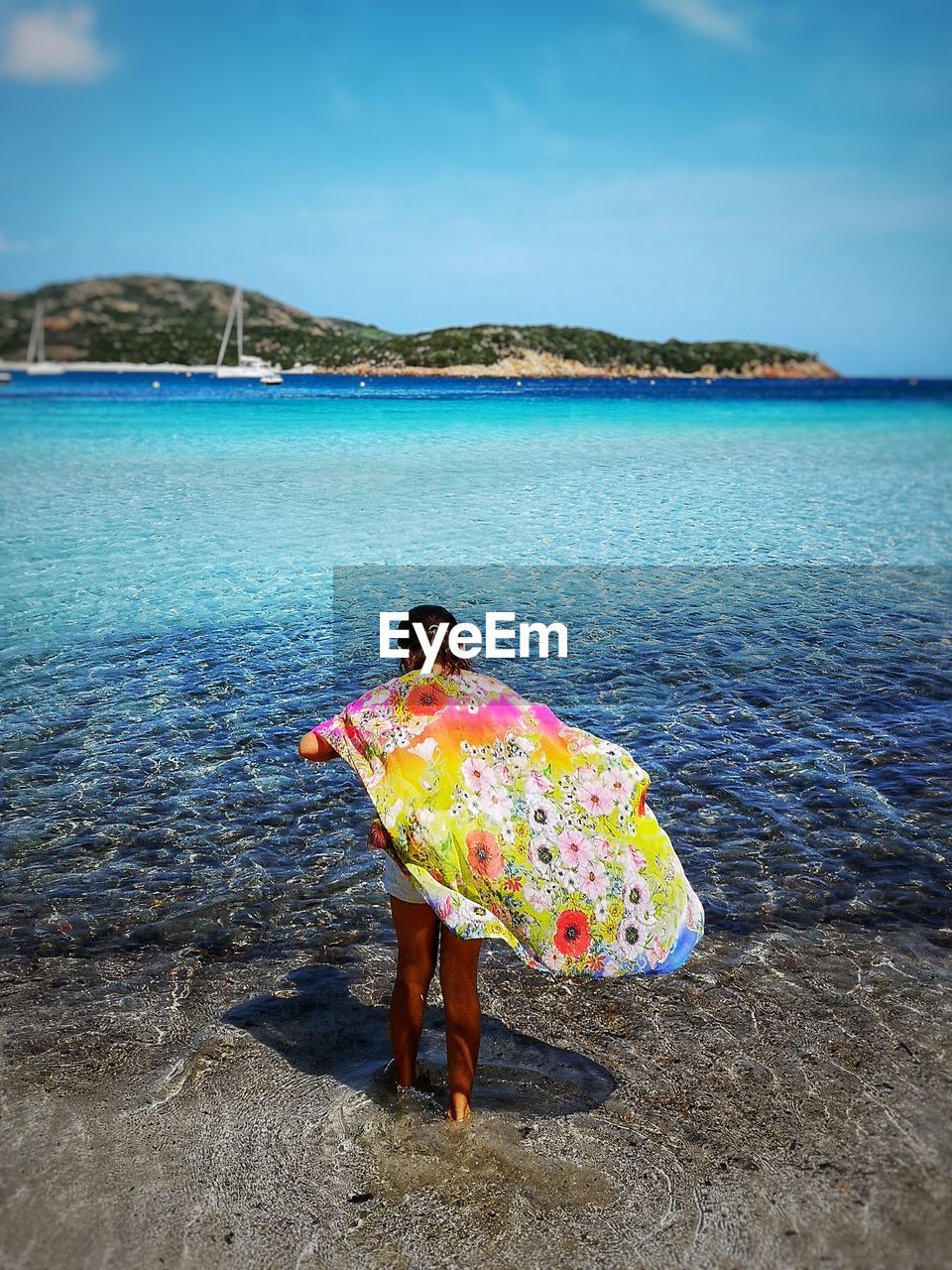 Rear view of teenage girl with scarf standing at beach