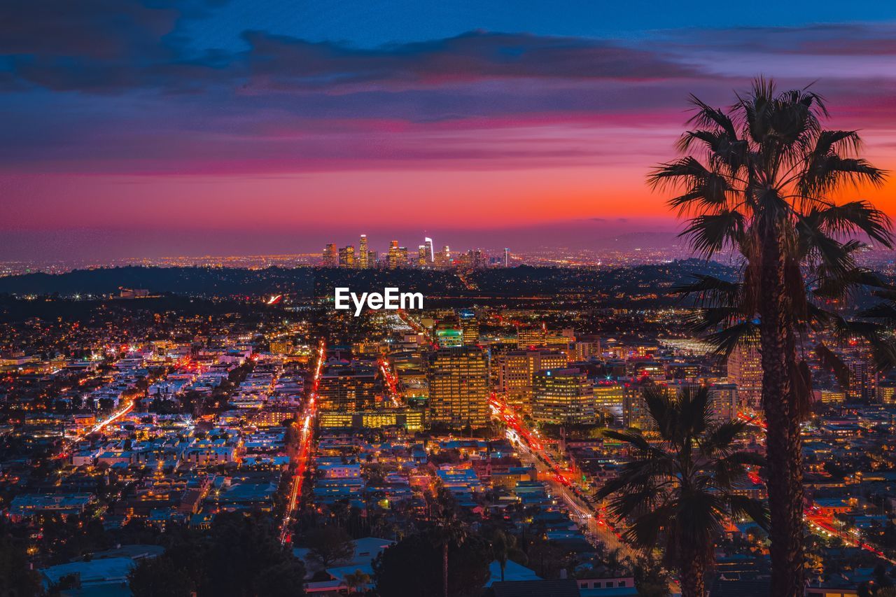 High angle view of city lit up at sunset