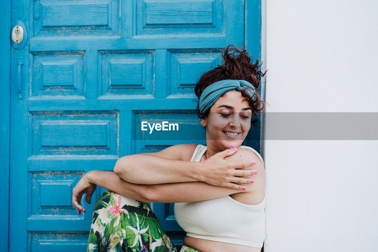 Portrait of smiling young woman standing against door