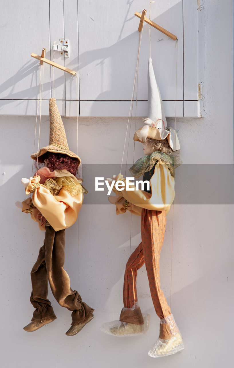 Two traditional greek handicraft puppets hanging on a wall in the village of oia in greece
