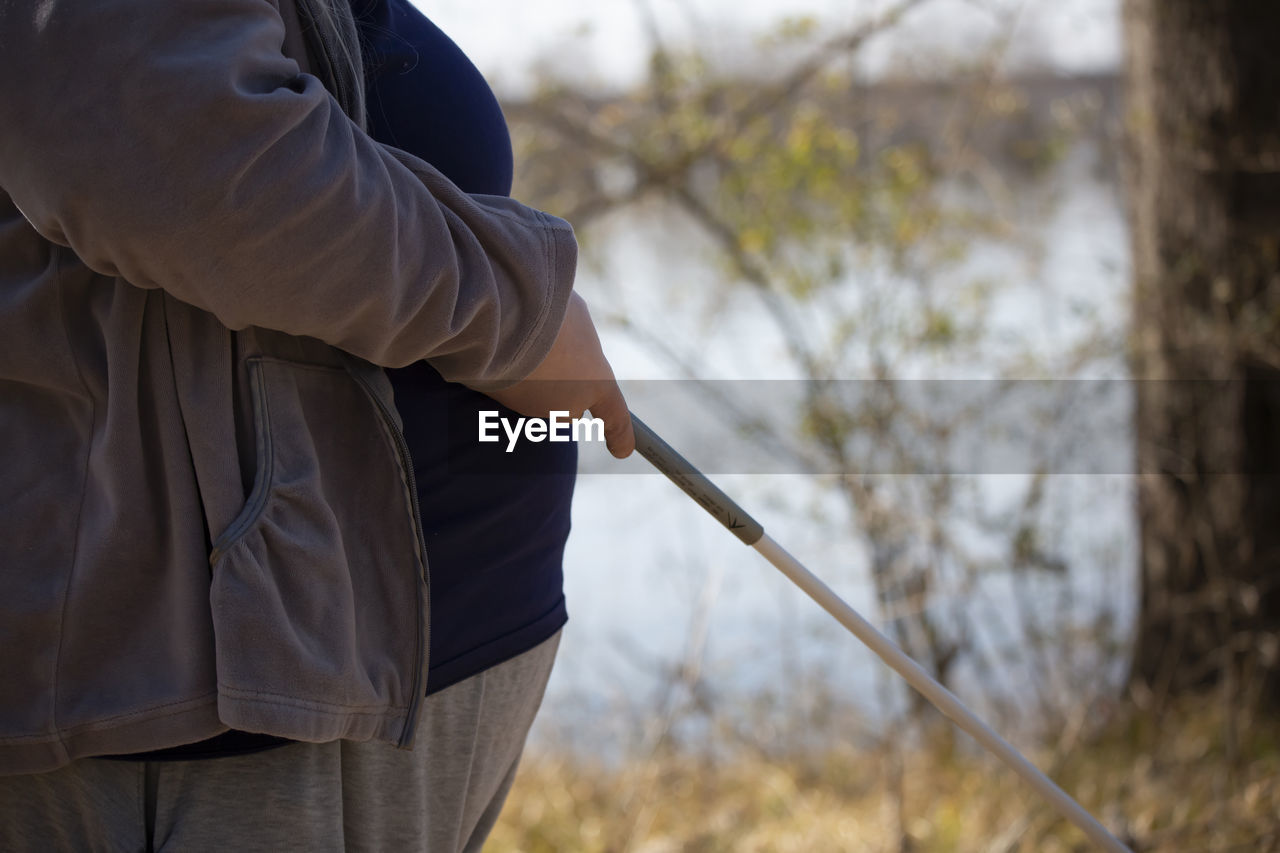 one person, adult, nature, tree, spring, standing, men, focus on foreground, clothing, jacket, day, plant, outdoors, autumn, leisure activity, forest, holding, lifestyles, land, person, weapon, midsection, activity, rear view