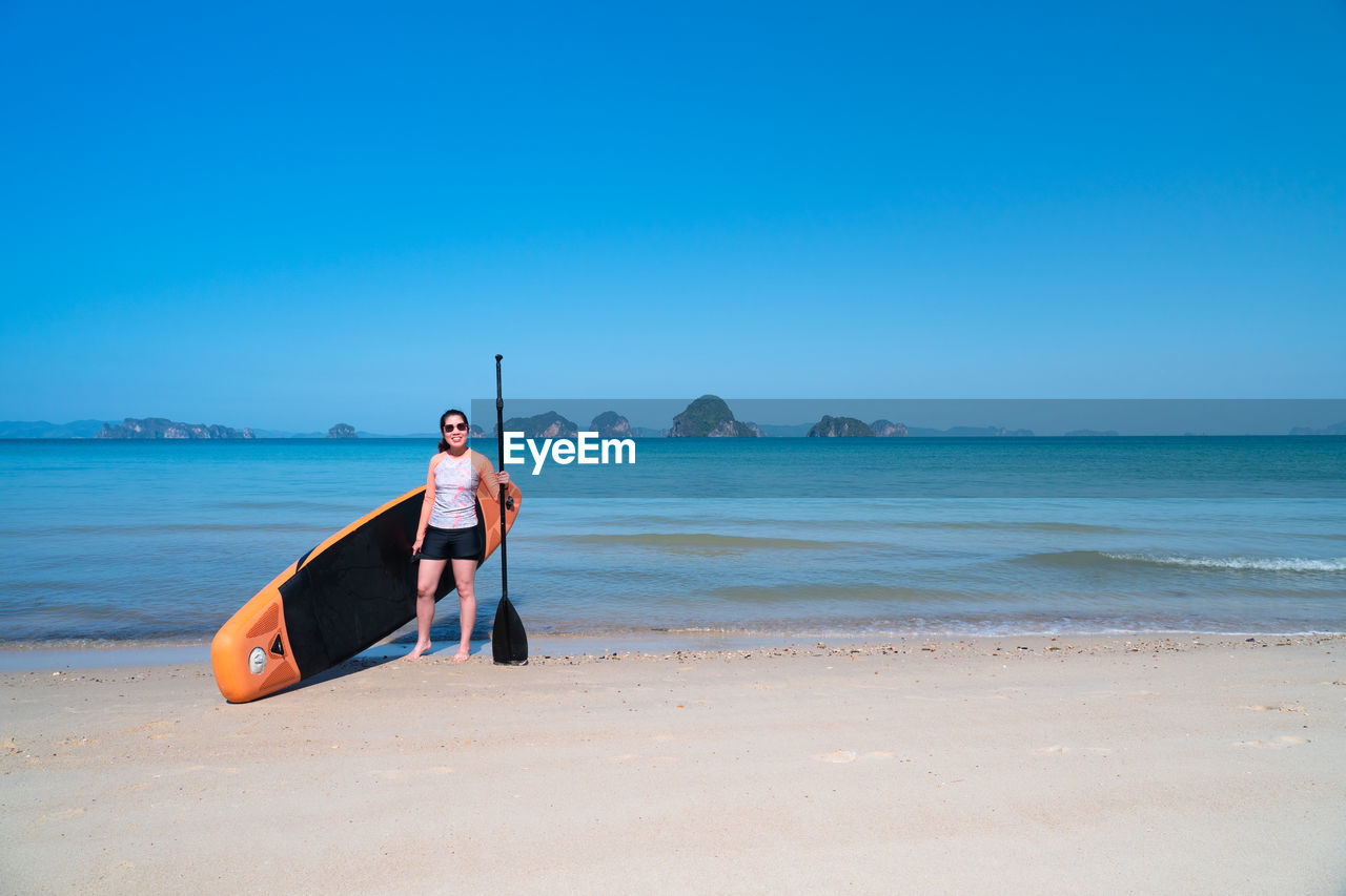 Woman holding oar at beach