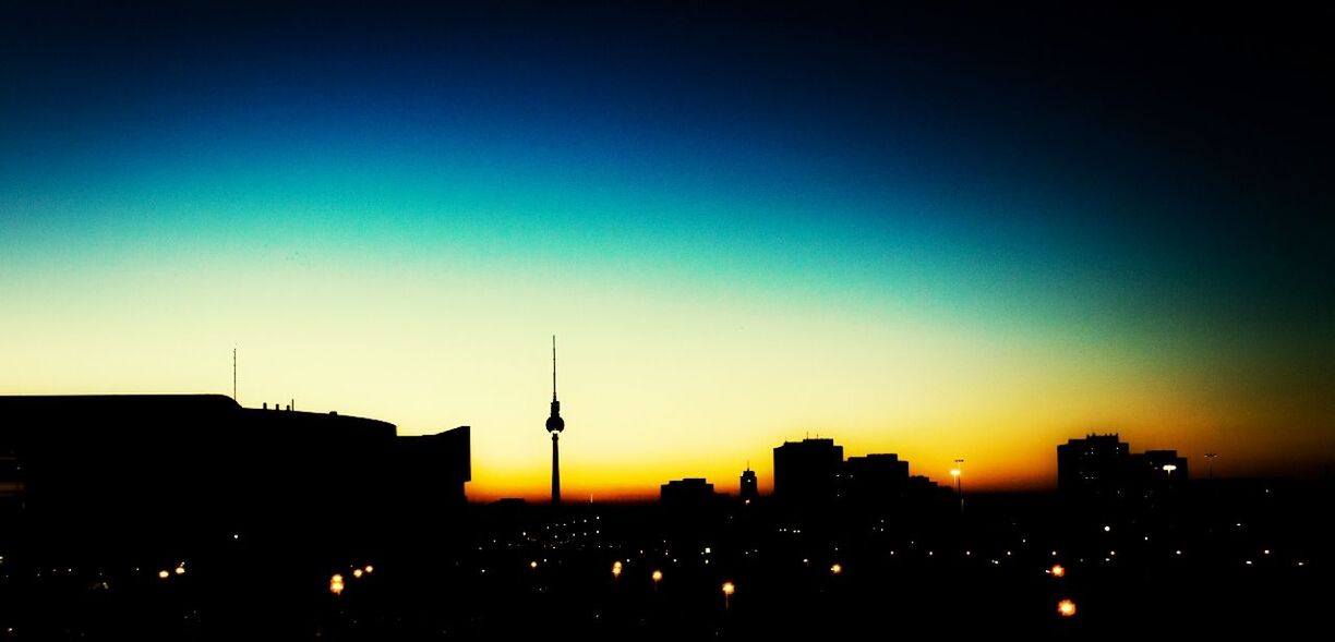 Silhouette city with fernsehturm against clear sky during sunset