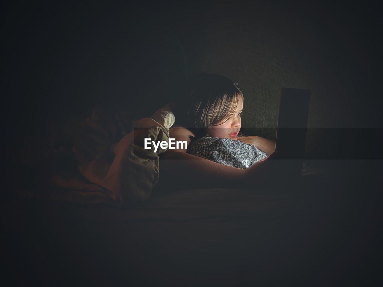 Ten-year-old girl using laptop in bed