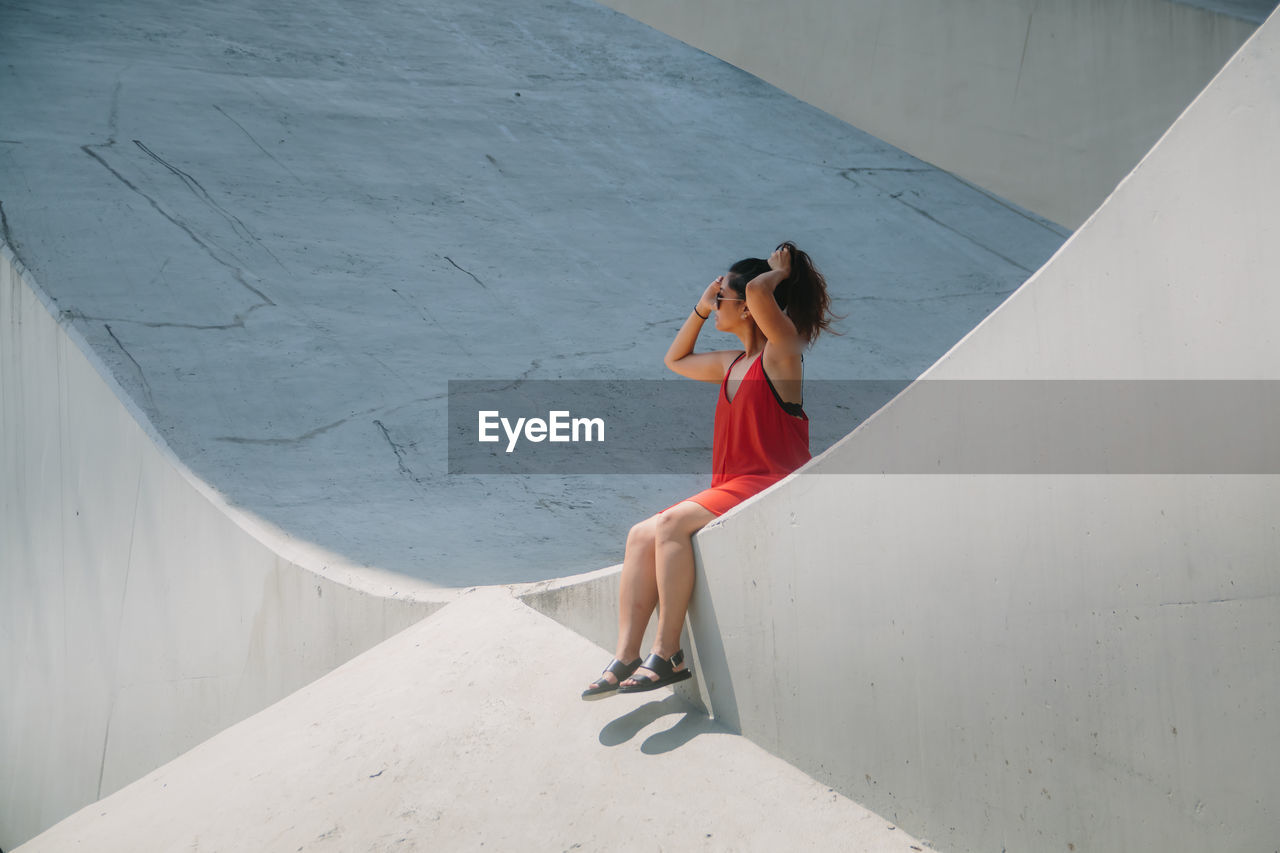 FULL LENGTH OF YOUNG WOMAN STANDING ON RAILING