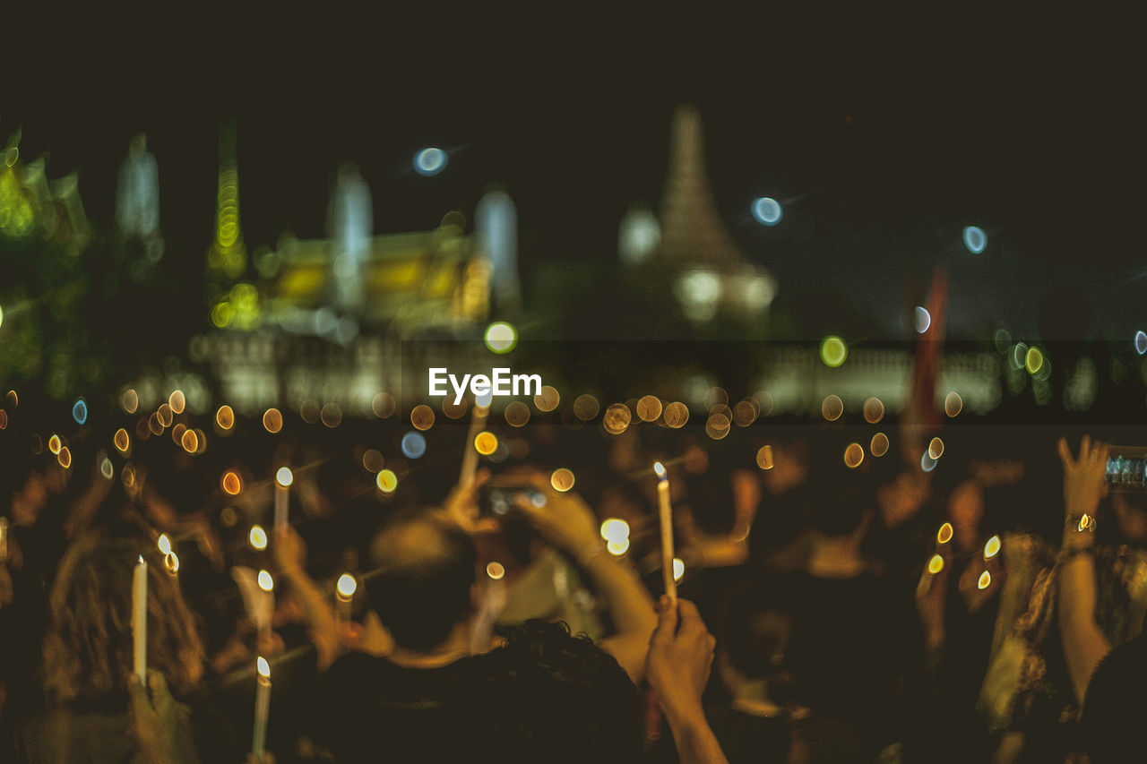 Defocused image of people with lit candles at music concert
