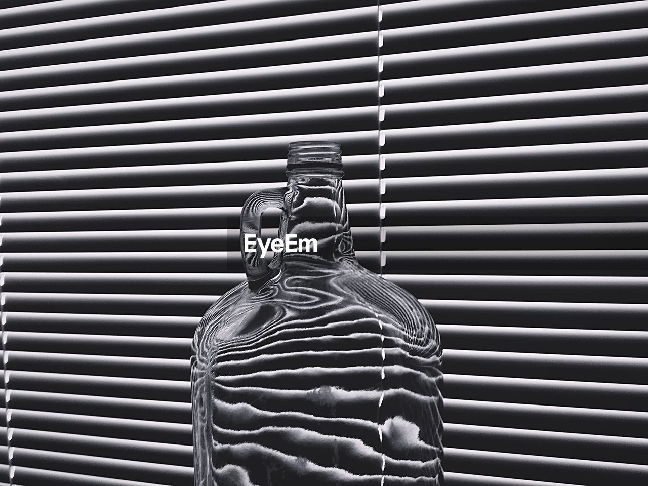 Close-up of glass jar against blinds