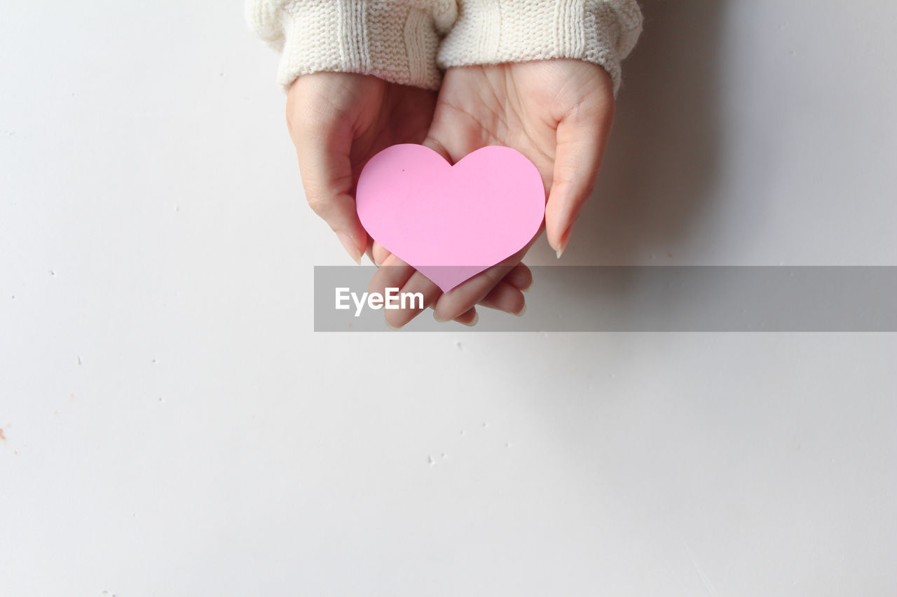 pink, heart shape, positive emotion, love, emotion, hand, heart, valentine's day, one person, copy space, finger, indoors, holding, creativity, childhood, women, studio shot, petal, toddler, adult, romance, close-up, skin, child, female, white background