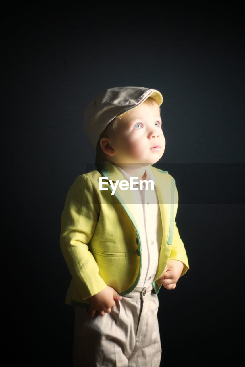 Cute baby boy standing against black background