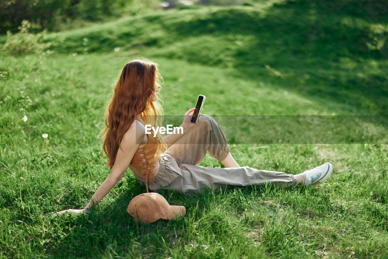 Rear view of woman sitting on grassy field