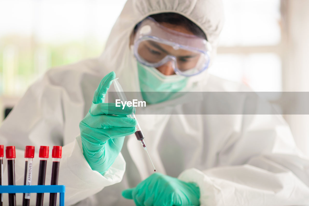 Smiling doctor wearing protective mask standing in laboratory