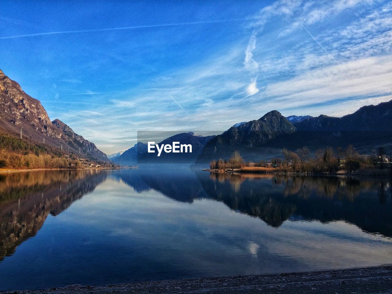 Scenic view of lake and mountains against blue sky