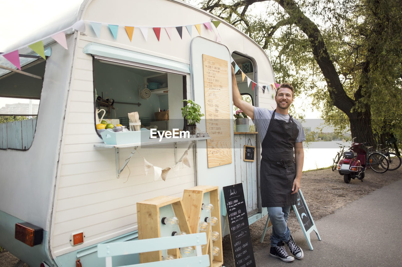 Portrait of confident male owner standing outside food truck on street