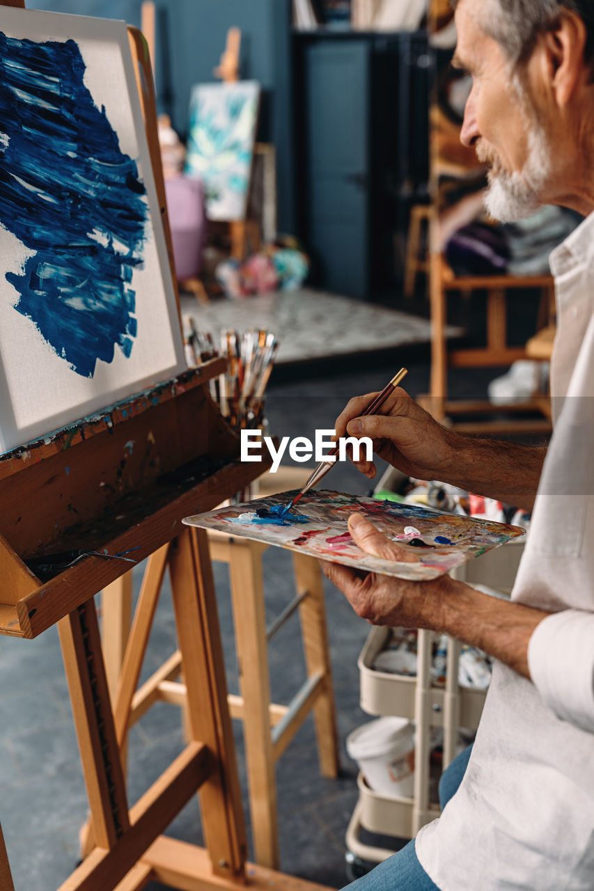 Senior man painting on easel