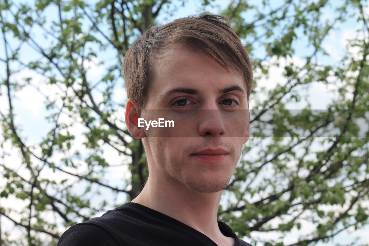 Close-up portrait of young man against trees