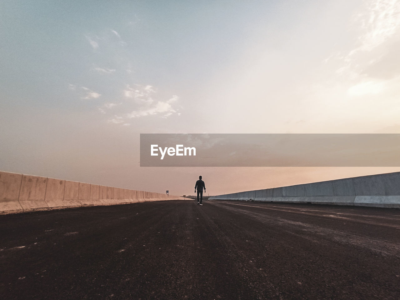 Rear view of man walking on road against sky