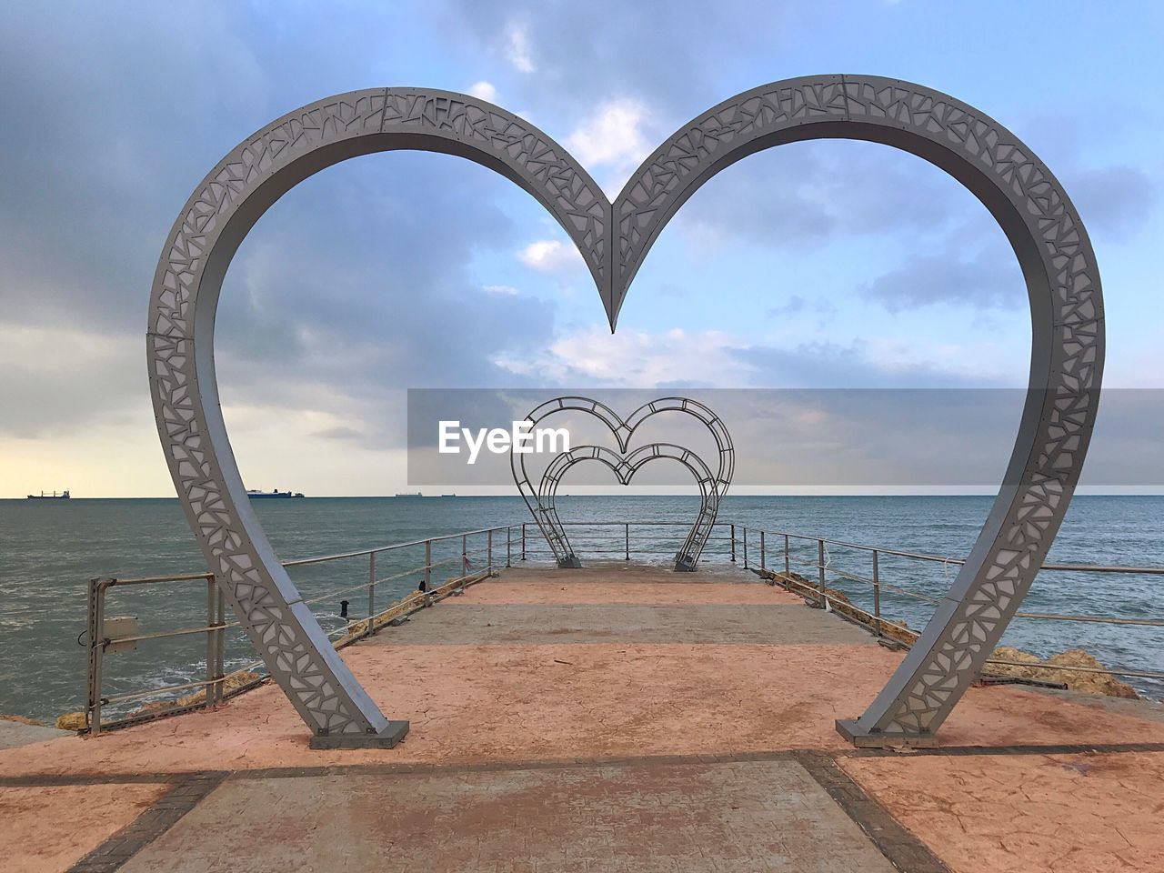 SCENIC VIEW OF SEA AGAINST SKY SEEN THROUGH METAL RAILING