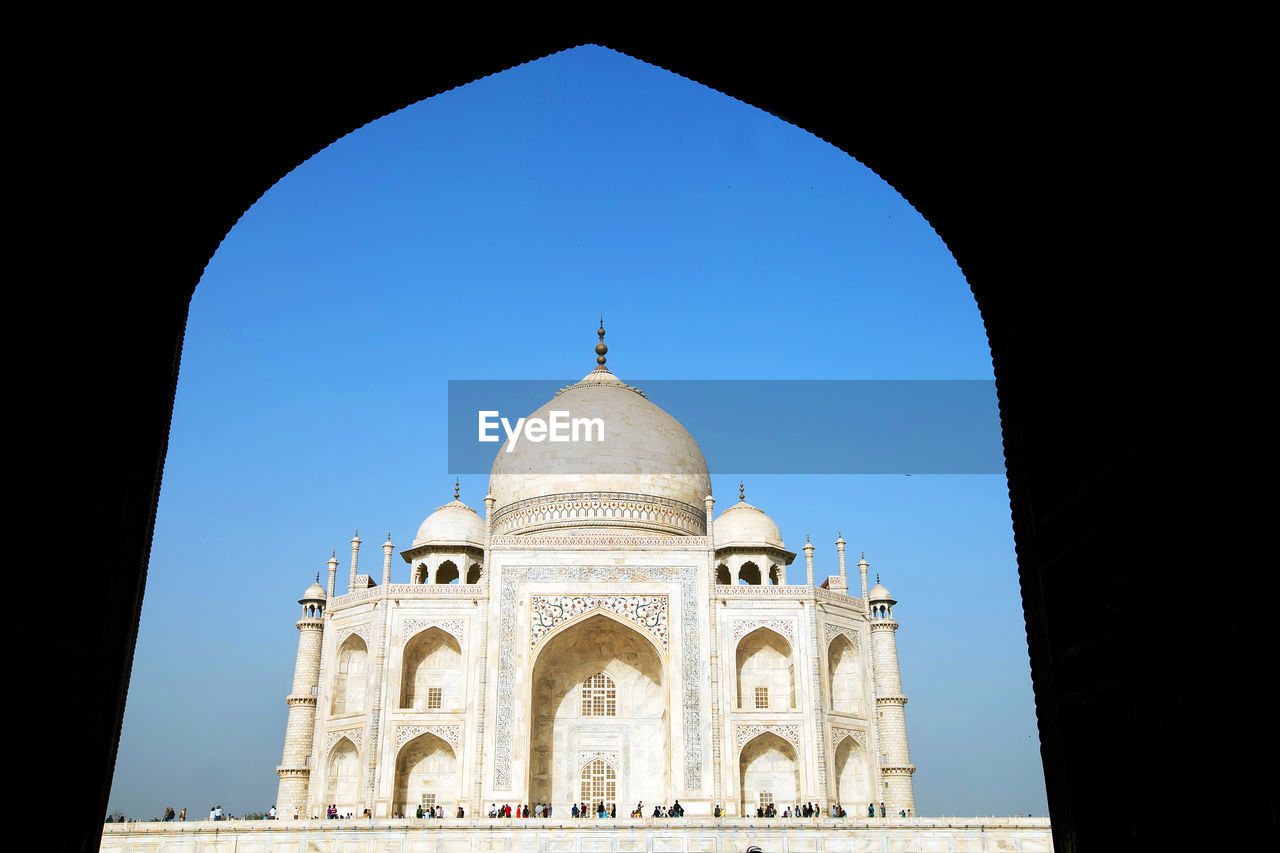 Low angle view of taj mahal seen through arch against clear sky