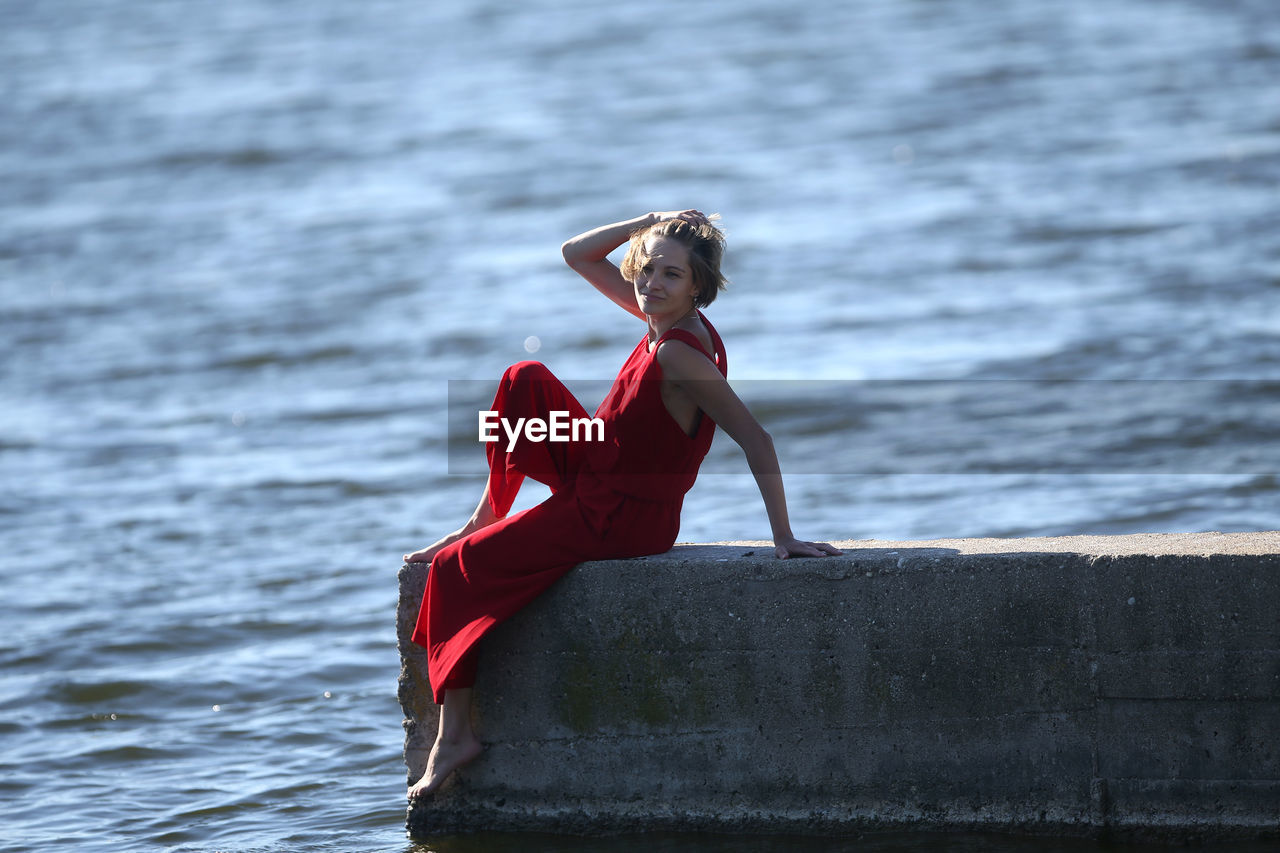 rear view of woman sitting on pier