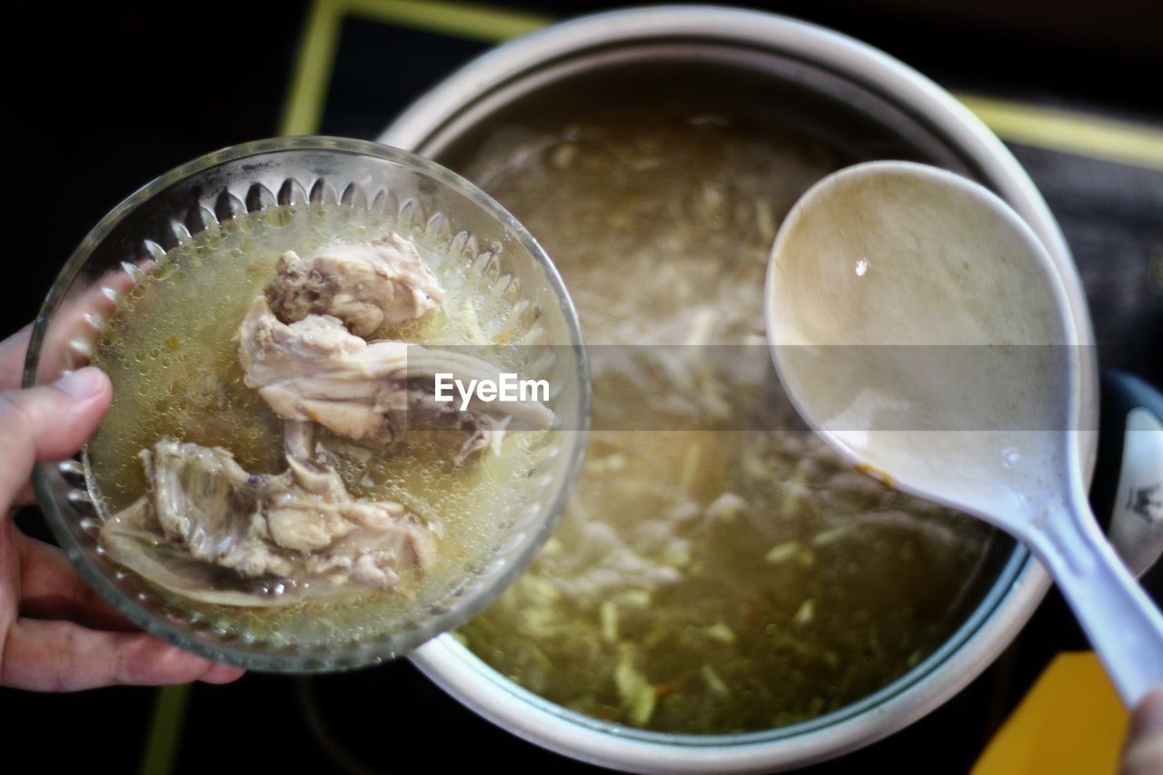 Close-up of hand holding soup in bowl