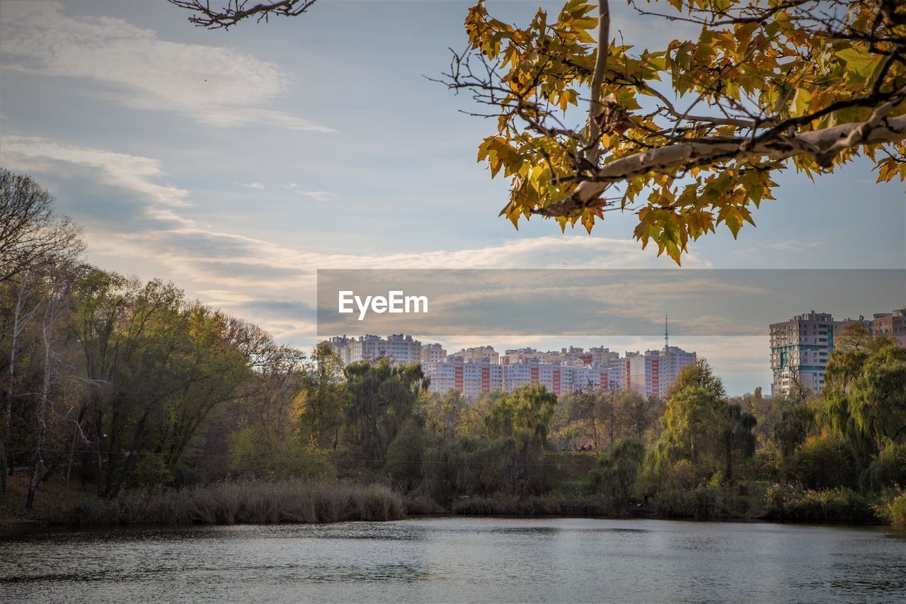 RIVER BY TREES AND BUILDINGS AGAINST SKY