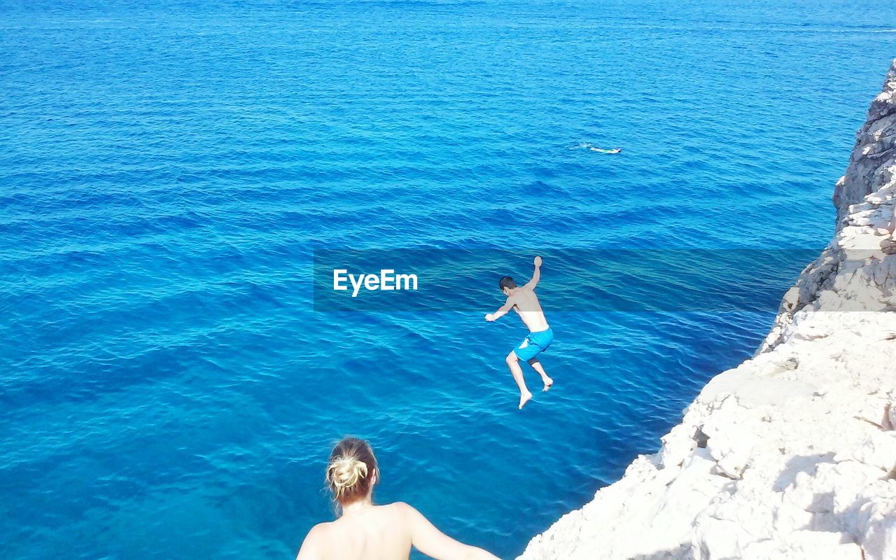 HIGH ANGLE VIEW OF YOUNG WOMAN SWIMMING UNDERWATER