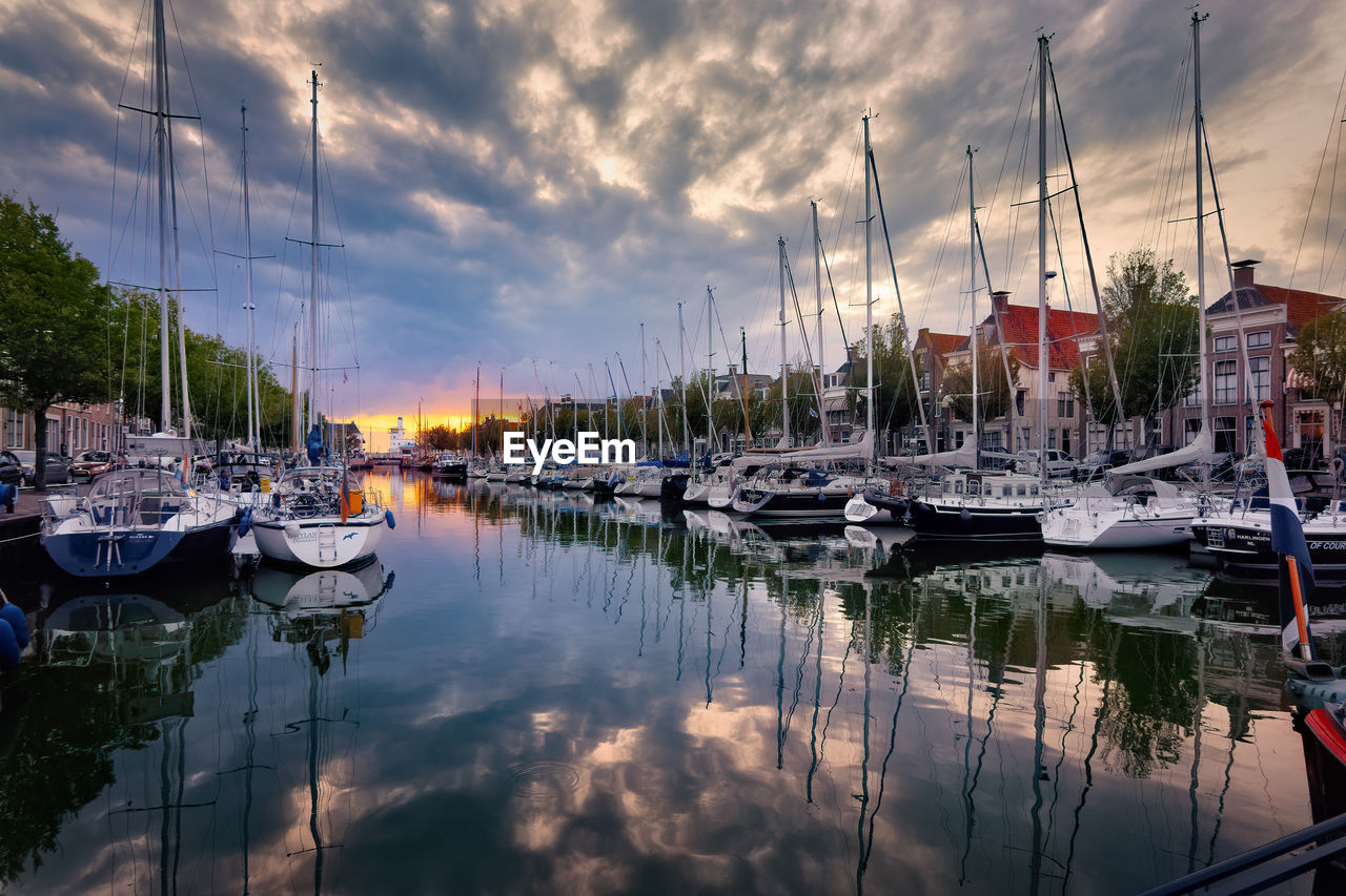 Boats moored at harbor during sunset