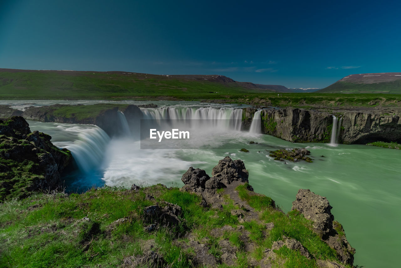 scenic view of waterfall against clear blue sky