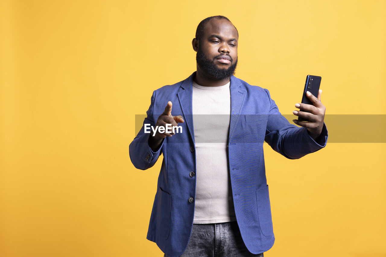 portrait of young man using mobile phone against blue background