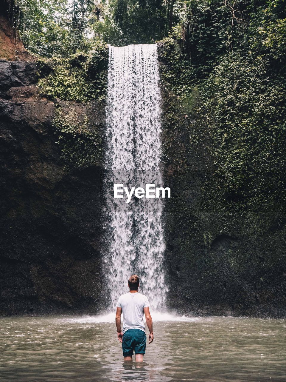 Rear view of man looking at waterfall