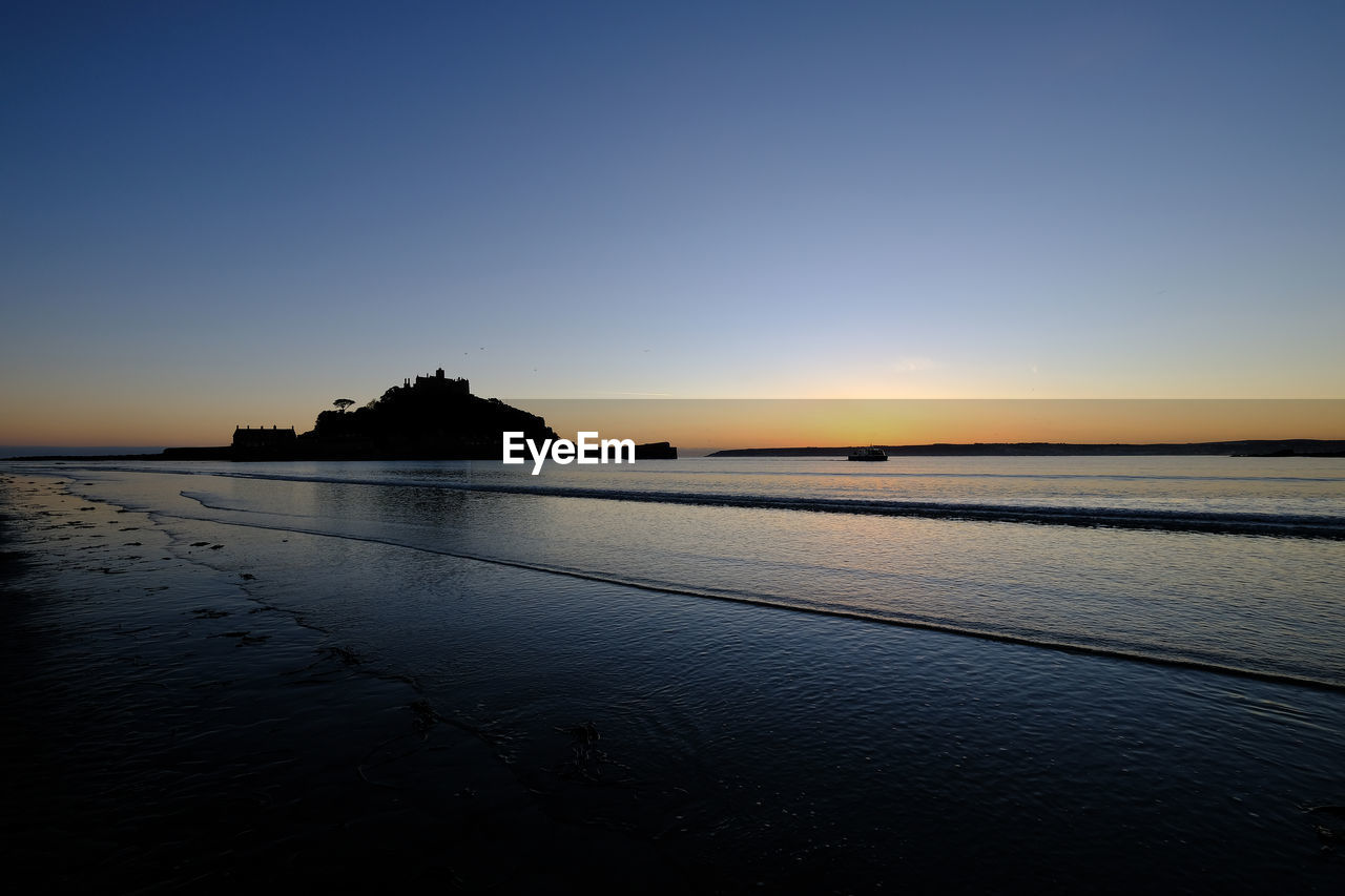 Scenic view of sea against clear sky at sunset