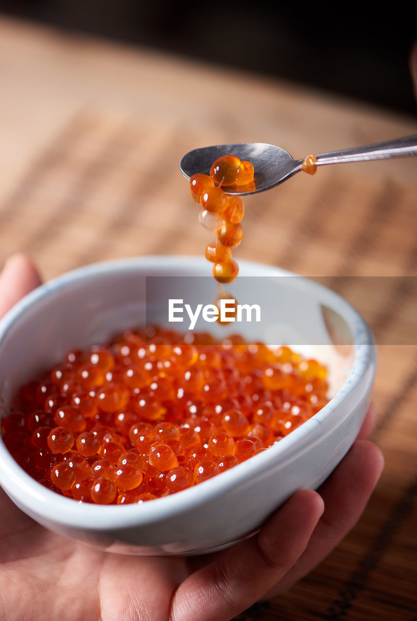 Close-up of hand holding caviar in bowl