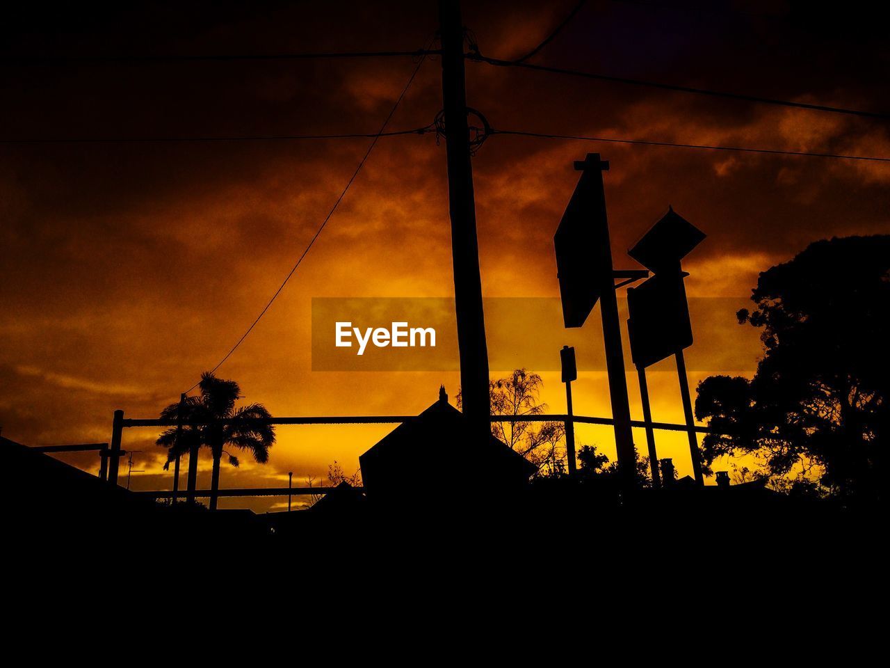 Low angle view of silhouette power line against sky during sunset