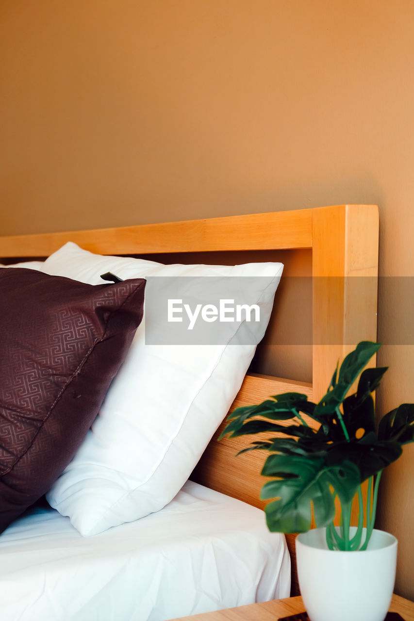 HIGH ANGLE VIEW OF POTTED PLANT ON TABLE BY BED