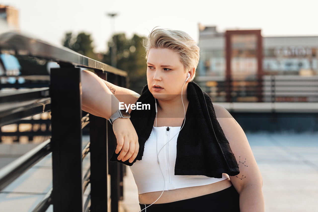 Young woman looking away while standing outdoors