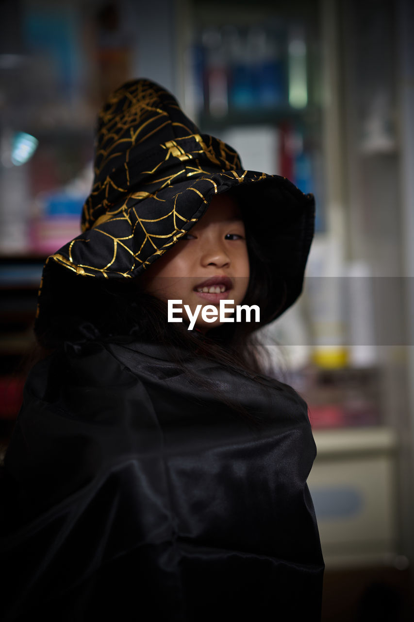 Portrait of smiling girl wearing witch at home